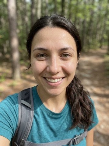 Mid-hike selfie of Mia with a backpack strap